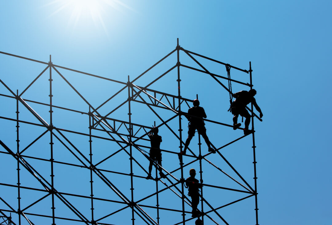 Silhouette,Of,Construction,Workers,On,Scaffold,Working,Under,A,Blue